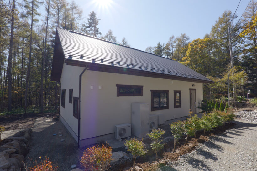 木々に囲まれた白い外壁の2階建住宅