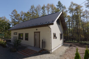 木々に囲まれた白い外壁の平屋住宅の外観