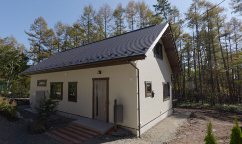 木々に囲まれた白い外壁の平屋住宅の外観