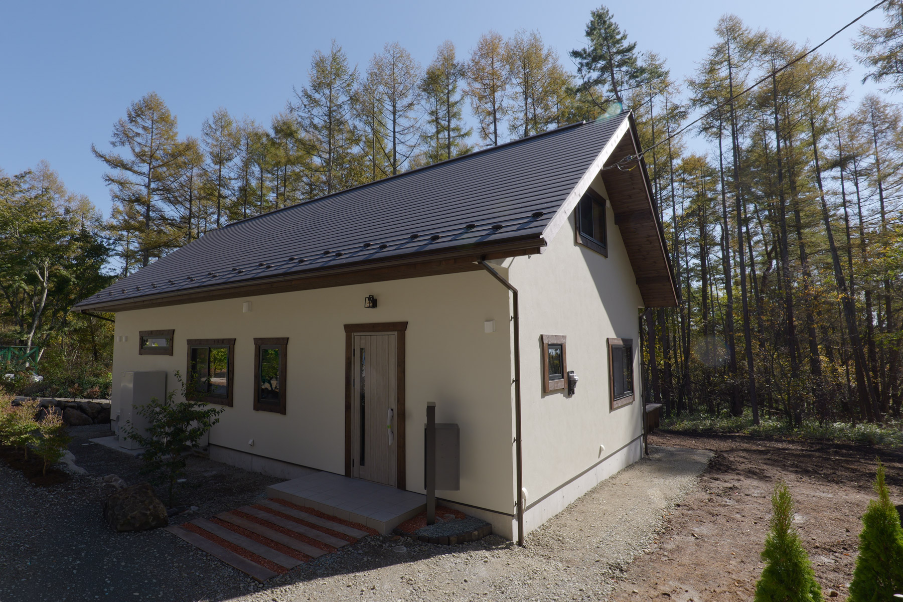 木々に囲まれた白い外壁の平屋住宅の外観